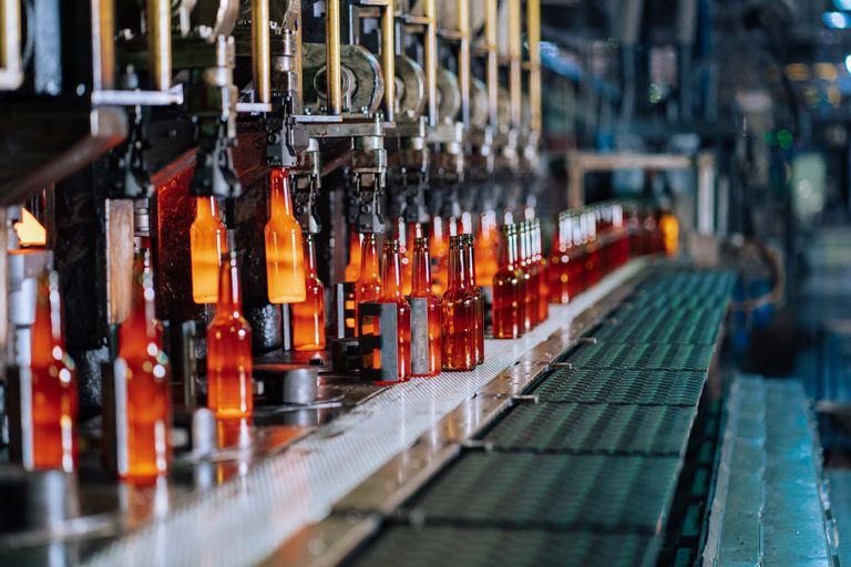 Glass bottles being manufactured on an automated production line in a factory.