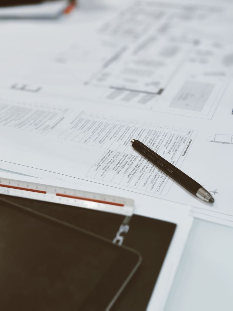 Top view of architectural blueprints, pen, and scale ruler on a designer's desk, showcasing a creative workspace.
