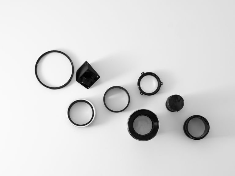 Top view of various camera lens components arranged on a white background.